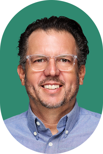 Man with short dark hair, glasses, and a beard smiling, wearing a light blue collared shirt. The solid green background provides a modern touch, while the oval frame gives the image a polished look—perfect for an AI professional’s profile.