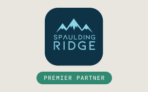 Logo featuring blue mountain peaks above the words Spaulding Ridge on a dark background, with a green rounded rectangle below containing the text Premier Partner in white capital letters.