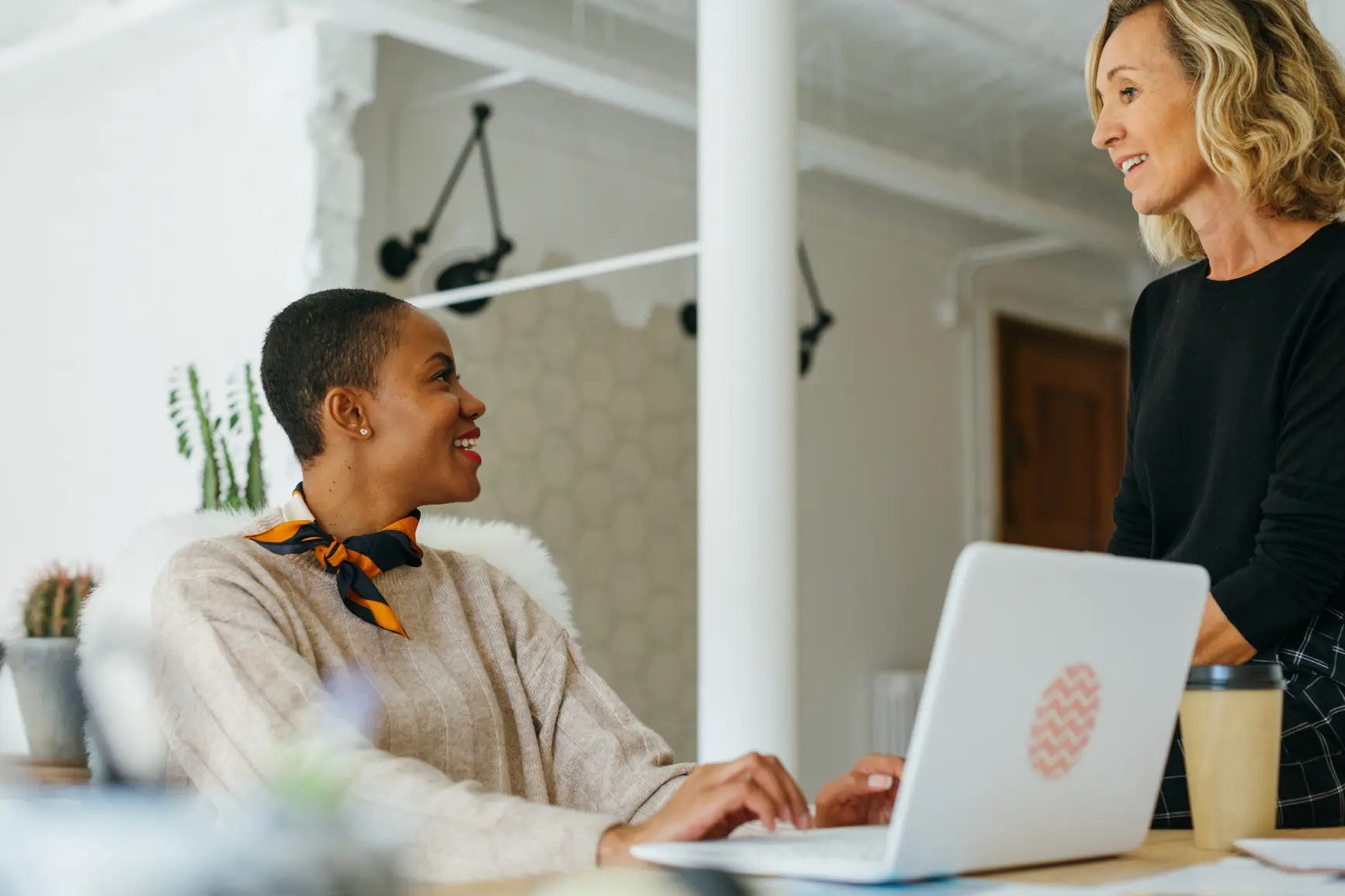 Business woman talking to a coworker while on the computer