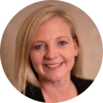 A woman with straight blonde hair smiles at the camera, exuding confidence in a black blazer over a light top. She is posed against a neutral, softly blurred background—an ideal image for an evisort alternative profile or professional bio.