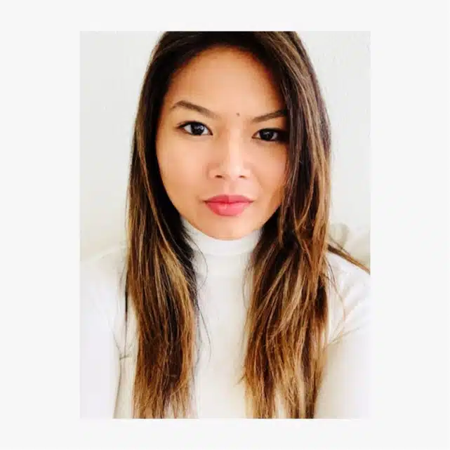 A woman with long, straight, light brown hair and a white turtleneck top looks directly at the camera against a plain white background.