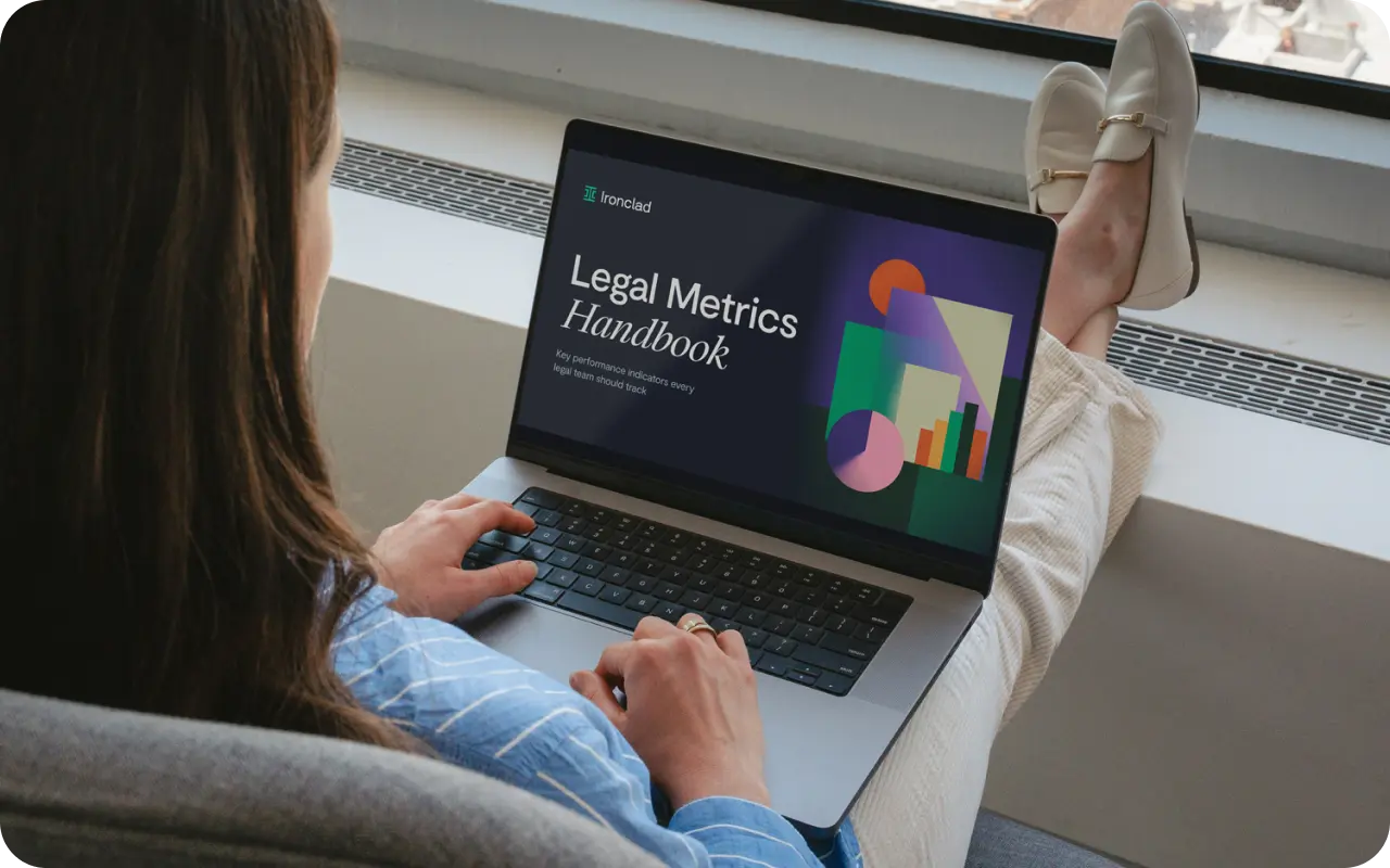 A person sits by a window with their feet up, using a laptop displaying a document titled Legal Metrics Handbook, featuring colorful geometric shapes on the screen that highlight key legal metrics.