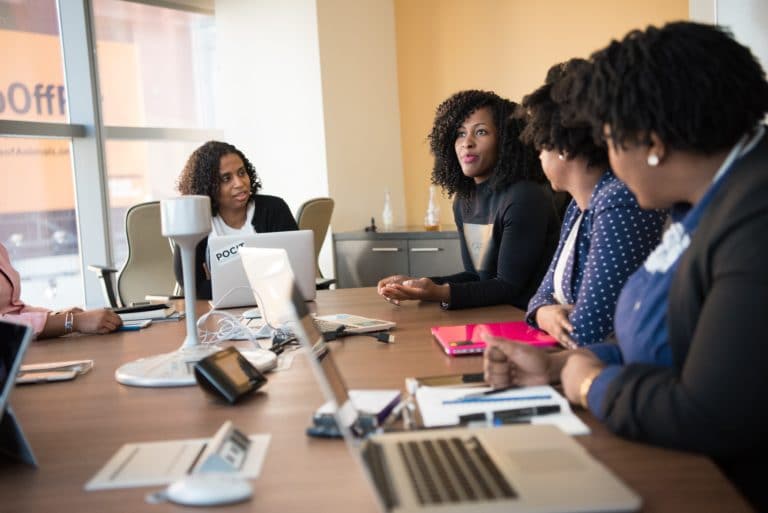 Group of black women sitting around a conference table smiling at each other | Letter of intent