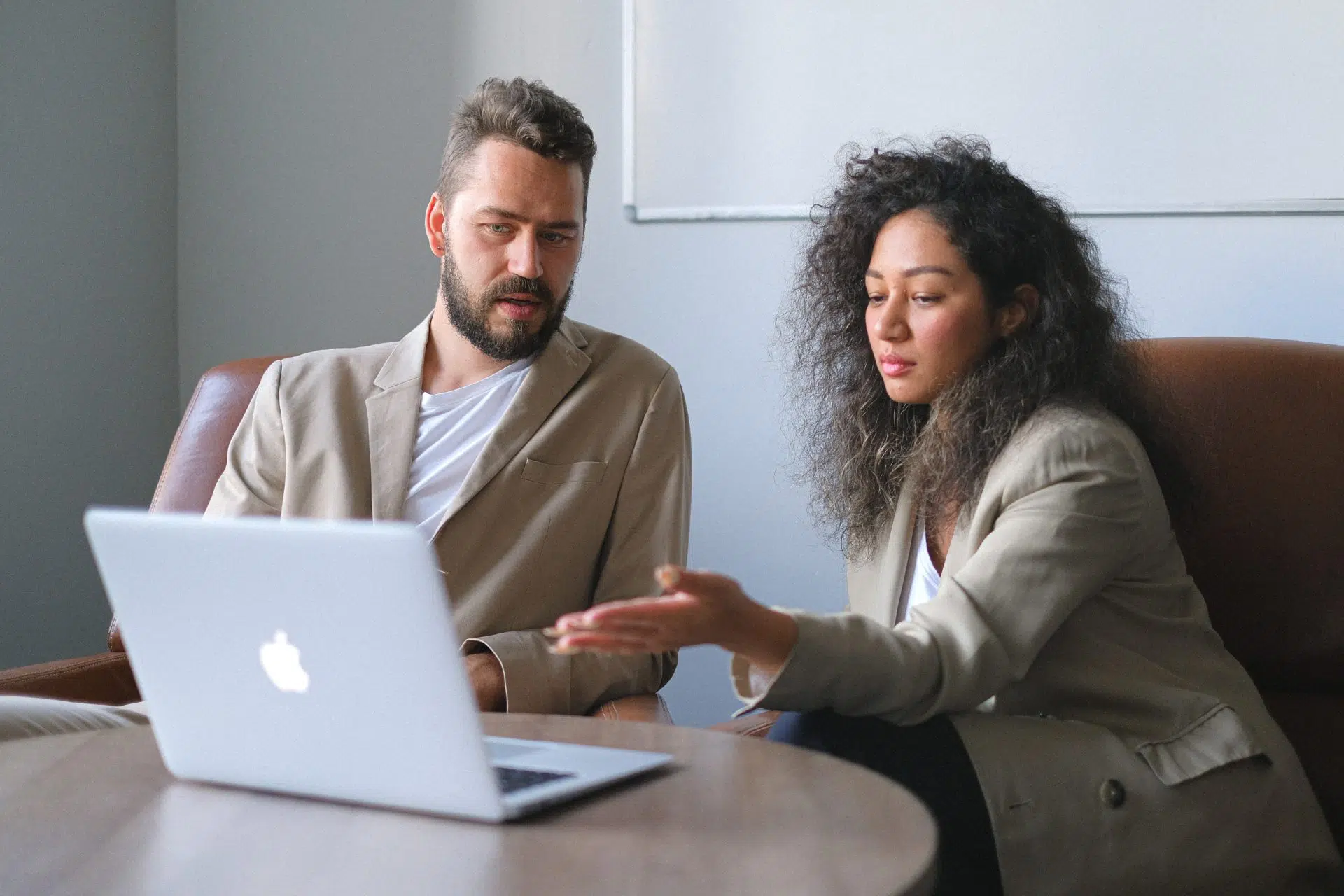 Two people sitting around a desk in front of a laptop looking at a contractual agreement