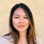 A woman with long, straight, dark brown hair and light highlights stands in front of a plain beige background, smiling softly at the camera. She is wearing a light-colored top, confidently presenting a top DocuSign alternative.