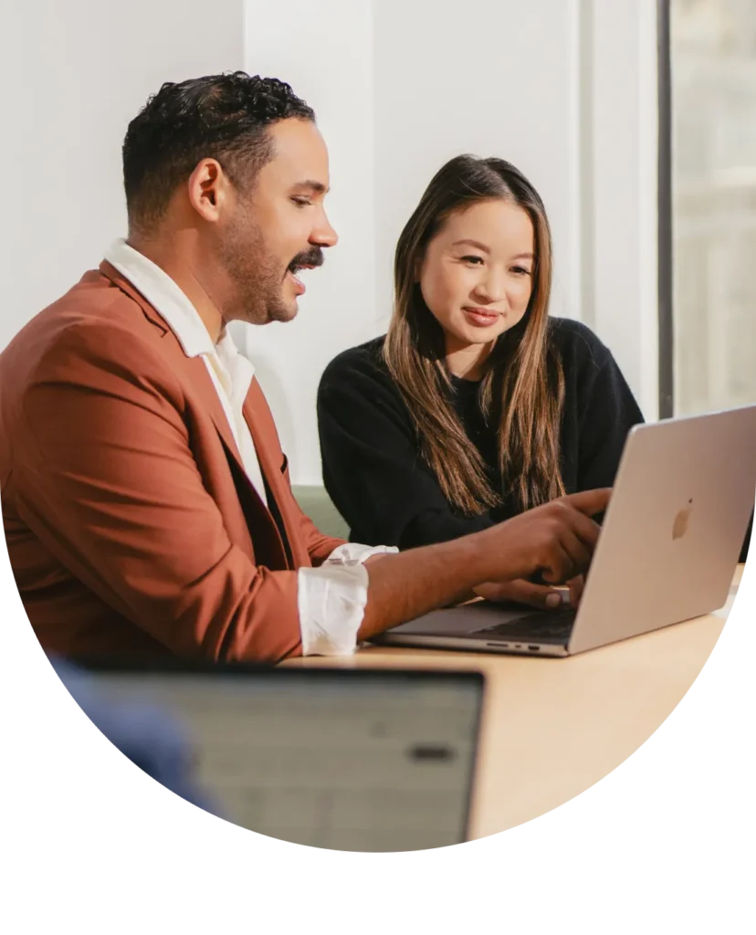 two people looking at a screen, with one person pointing to something on the laptop screen