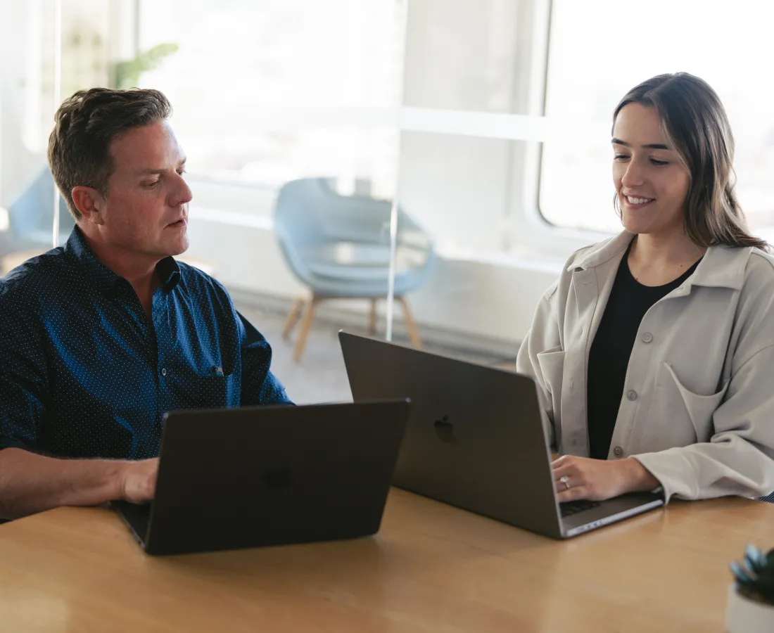 two people collaborating at their laptops