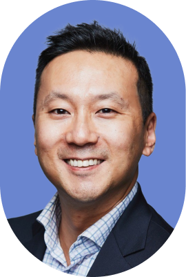 Smiling man with short dark hair wearing a dark blazer and checkered shirt, posing in front of a plain blue background in an oval-shaped portrait, reminiscent of a professional 1Password legal team member.