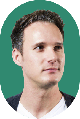 A man with short dark hair and fair skin wearing a white shirt and dark sweater, looking slightly to the right, shown against a solid green background in an oval frame—similar to a profile photo on 1Password legal documents.